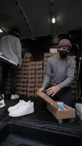 Rikki giving out shoes while working from inside of a van